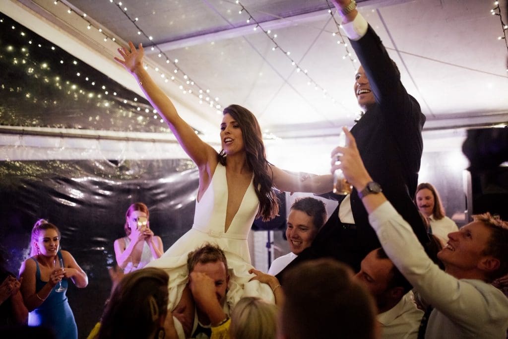 Bride And Groom On Shoulders Of Friends At Wedding Reception.jpeg