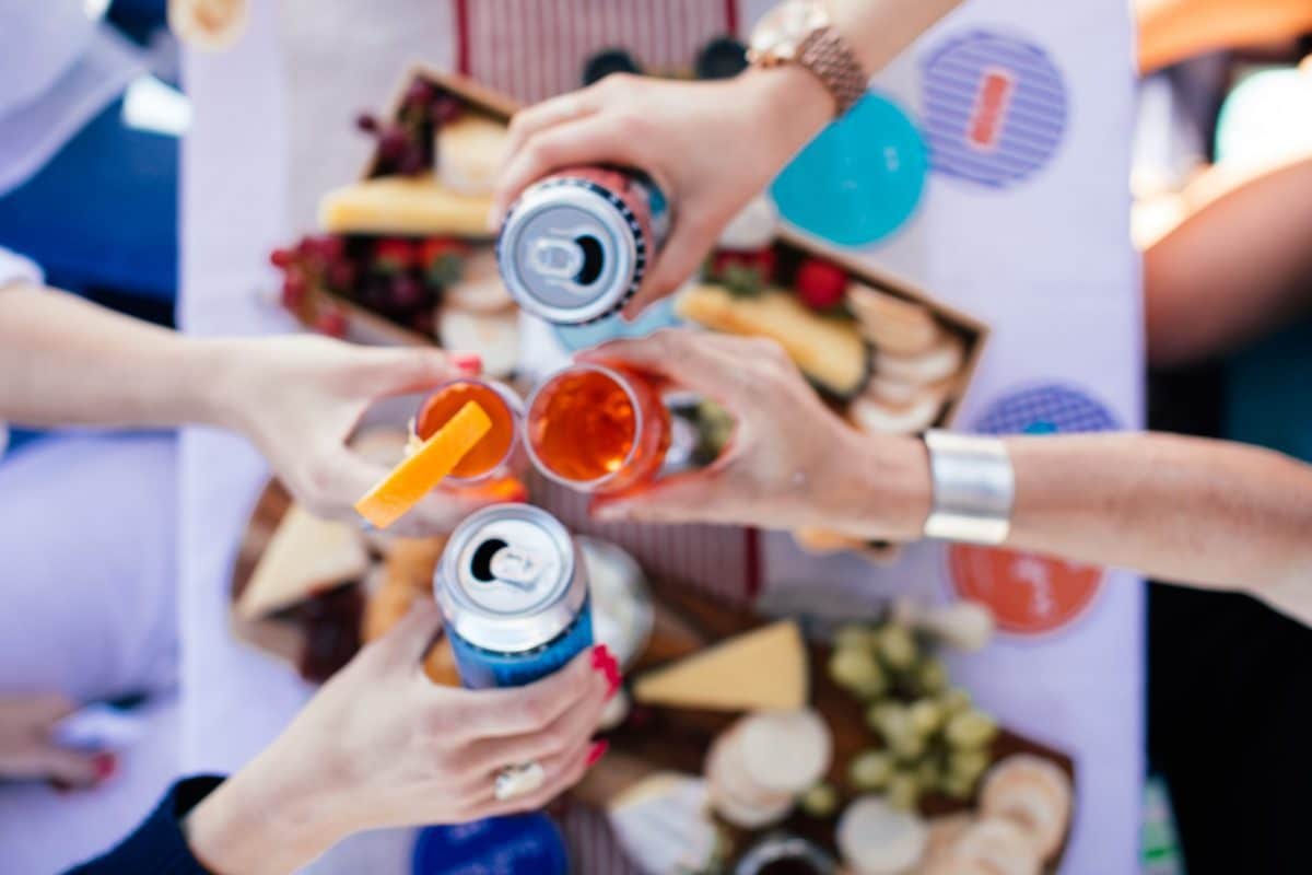 People Clinking Their Glasses Over A Grazing Table At A Party