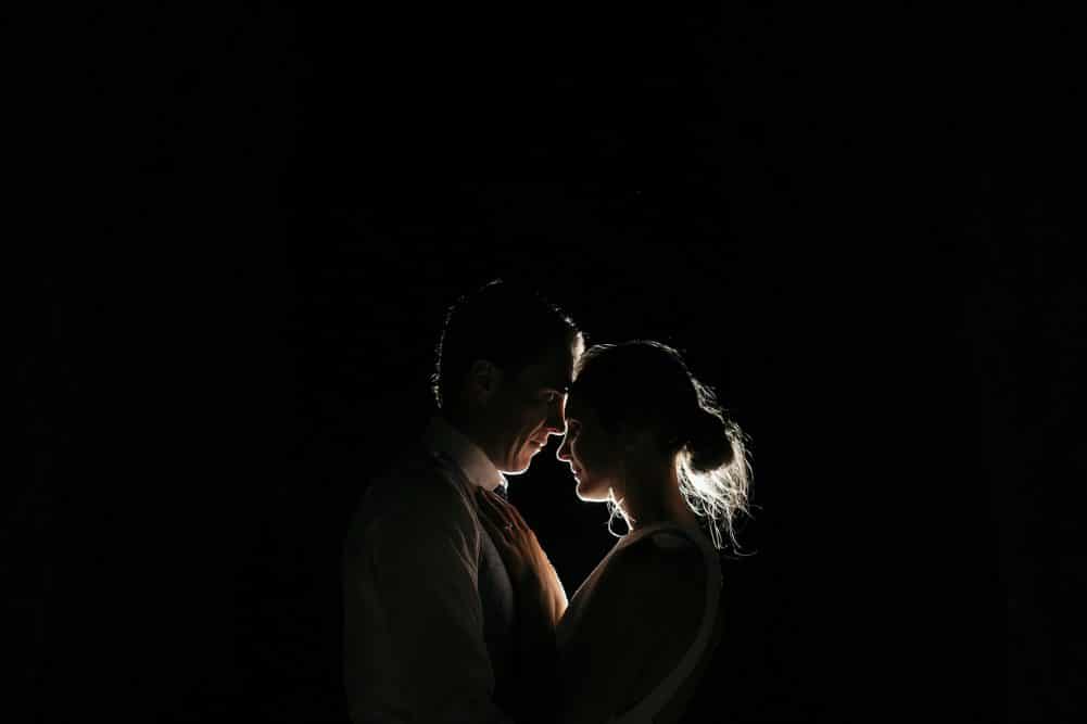 Bride And Groom Pose In Front Of A Light on Dark Background At Coombe Yarra Valley